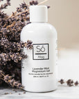 White bottle of Só Lavender Mint Magnesium Gel with lavender flowers on a light background