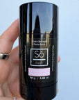 Black deodorant stick with 'Só Fresh Extra Strength Island Coconut' branding held by a hand against a light gray background