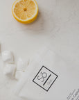 Packaging of Só Clean Citrus Dish Capsules with a lemon half on a marble surface