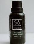 Black essential oil bottle labeled 'Sö Essential' Wild Balsam on a light gray background