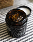 An open jar of Só Silver Mission Falls Ionic Silver Gel 100 ml on a black and white striped fabric surface, with the lid resting beside it.