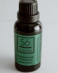 Black bottle of Só Holiday Essential Oil Blend in Candy Cane Lane scent on a light grey background.