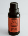 Black bottle of Só Essential Oil Blend in Holiday Spice on a light gray background