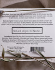 An image of the back of a white rectangular box of Só Sitz Bath Tea with black text listing directions and ingredients styled on a linen fabric background with natural elements.