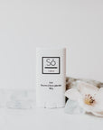 A white plastic deodorant style container branded Só Salve Ice Salve a cooling muscle salve in 10 g twist-up stick styled on a white backdrop with natural stone and floral elements