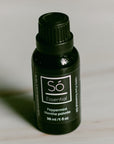A black bottle of Só Essential Oil labelled Peppermint 30 ml on a light grey background.