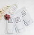 A flat-lay of Só products on a white marble surface with decorative flowers. The products include a clear spray bottle of Magnesium Oil, a white pouch of Coco Cream soak, a white pouch of Coconut & Oat Milk Bath, and a white pouch of Blush Soak.