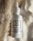 A white bottle labeled 'Só Oil' with fabric and floral elements
