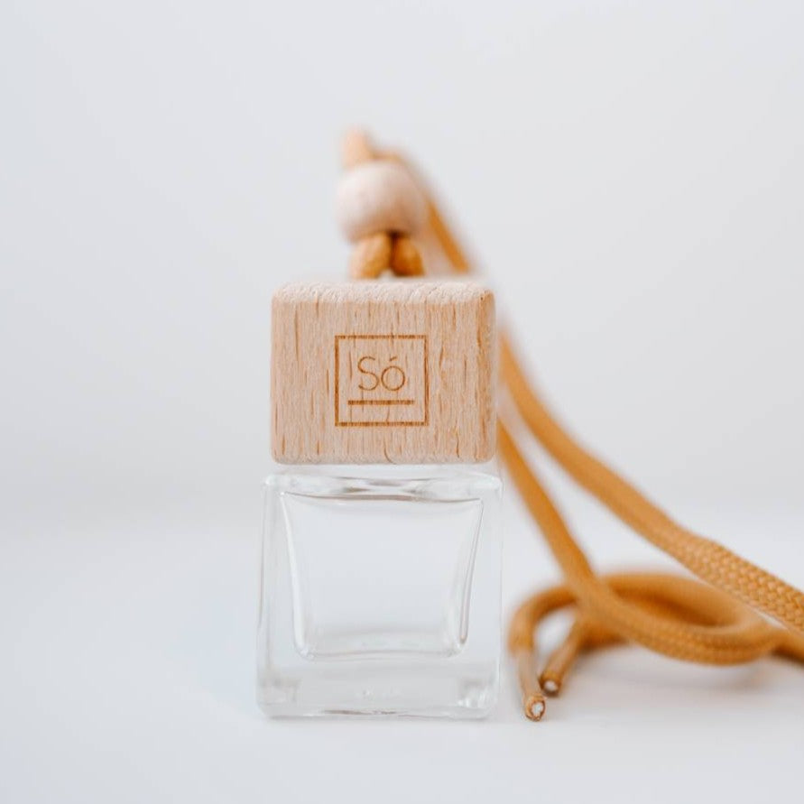 Small square glass jar with a Só branded wooden lid and wood bead with tan coloured shoelace-like string