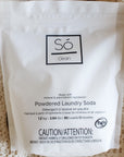 A white bag of Só Clean Powdered Laundry Soda on a textured beige fabric background.