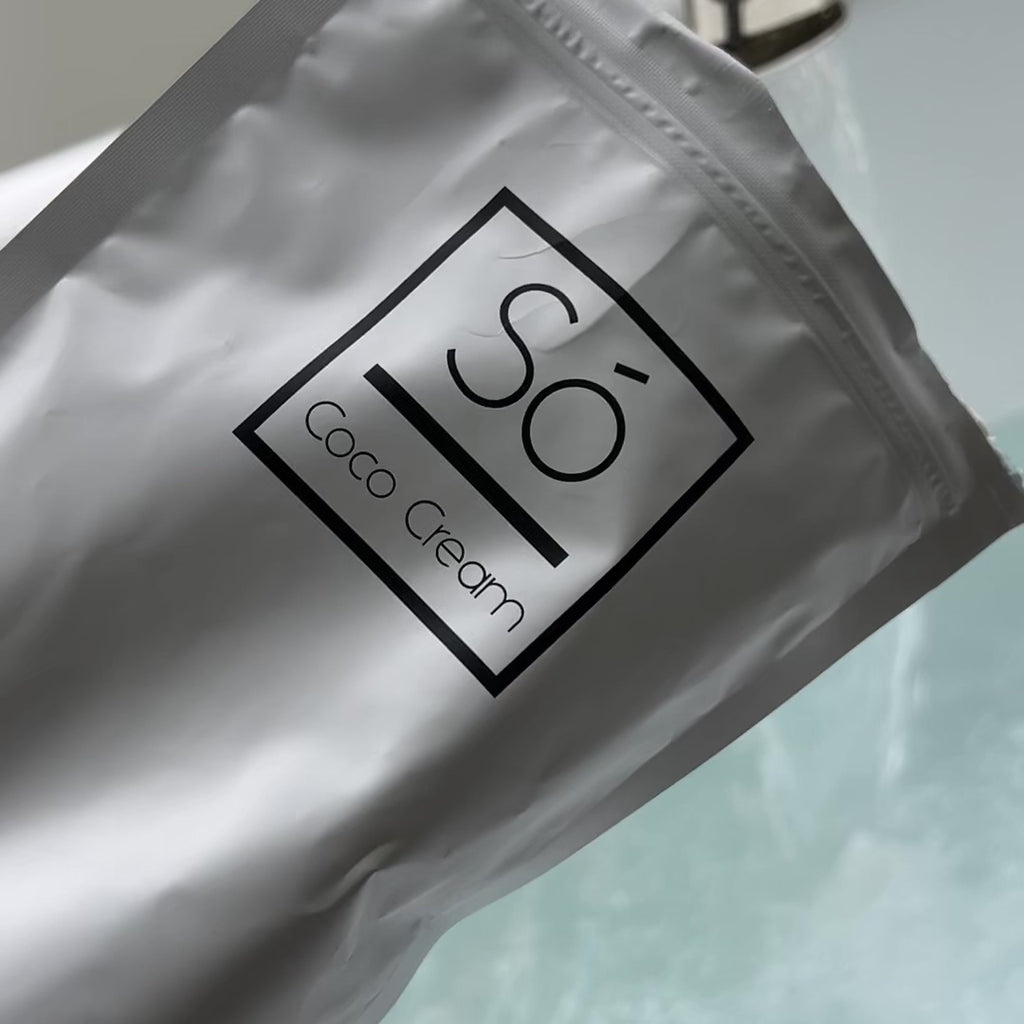 Video showing a Só Coco Cream bath soak being poured into a bath with running water and swirling water showing the product